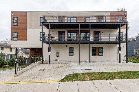 A modern two-story apartment building with a balcony on the second floor.