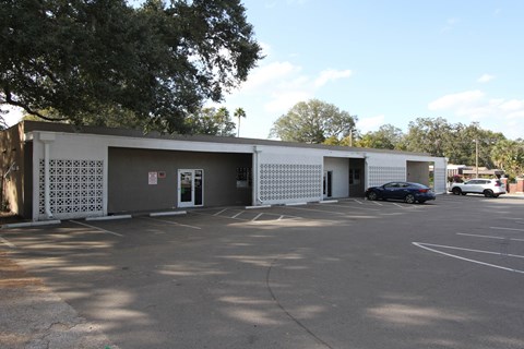 A parking lot with a building and cars parked in front.