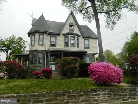 an old house with pink flowers in front of it