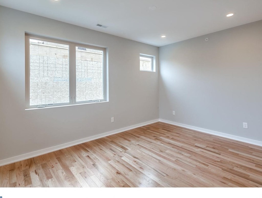 an empty living room with wood floors and two windows