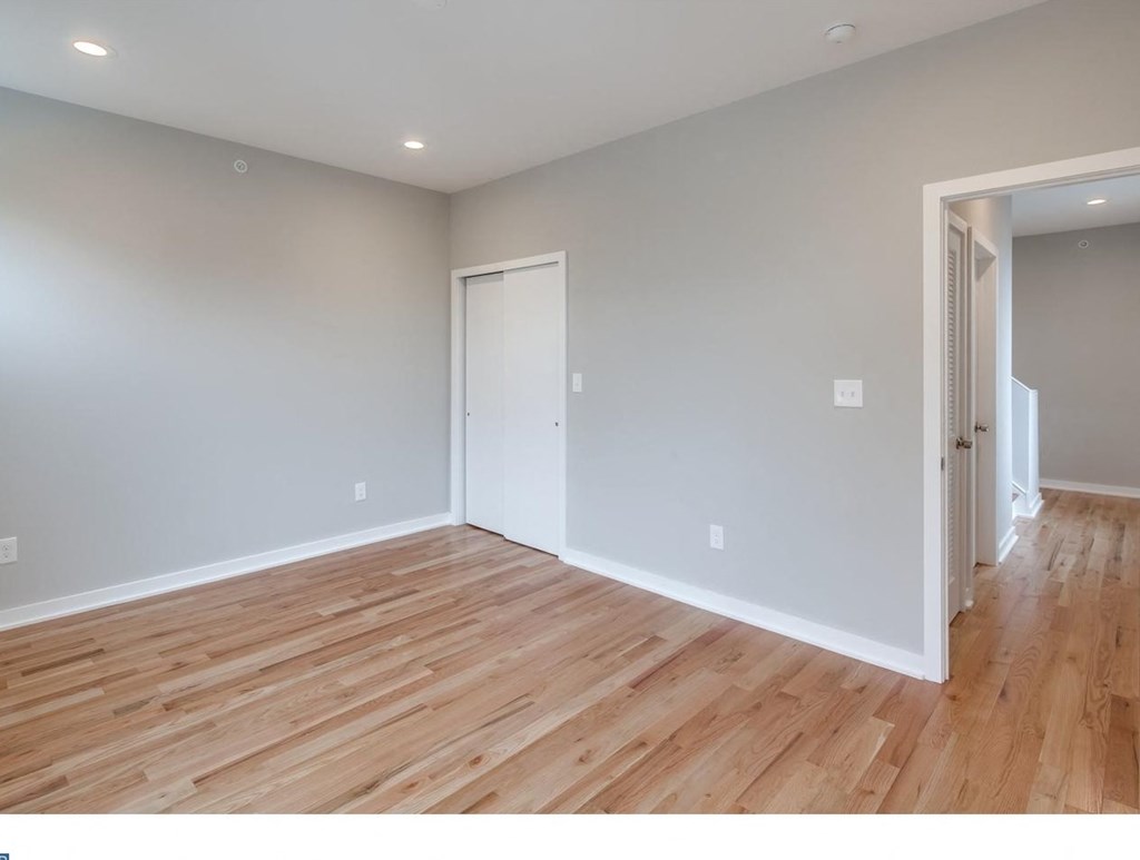 a living room with wood floors and a door to a hallway