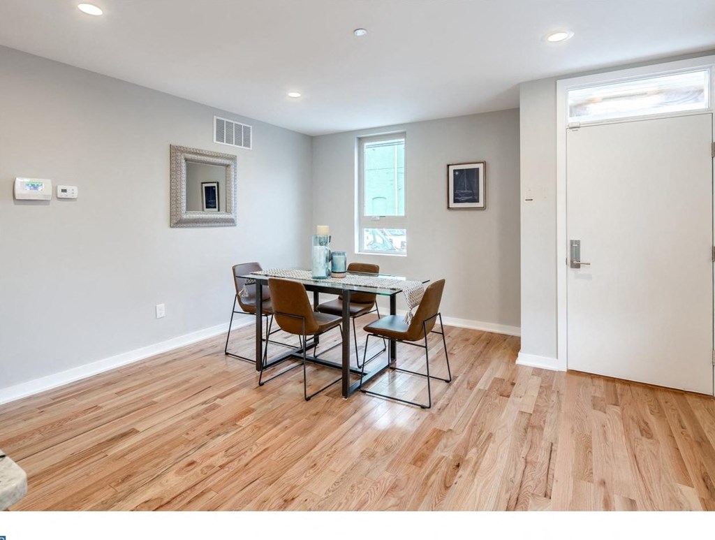 a dining room with a wooden floor and a table and chairs