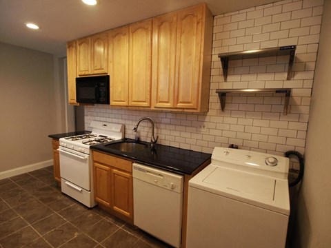 A kitchen with a white dishwasher and a black countertop.
