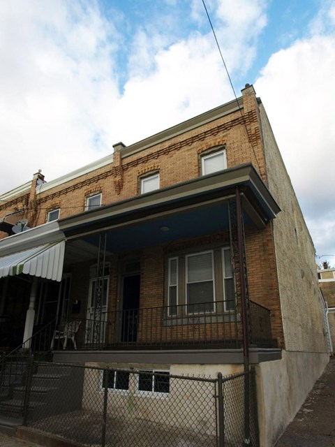 A brick building with a balcony and a fence.