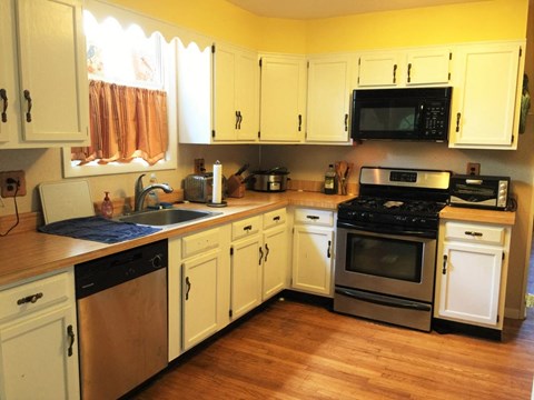 A kitchen with white cabinets and a black microwave above the stove.