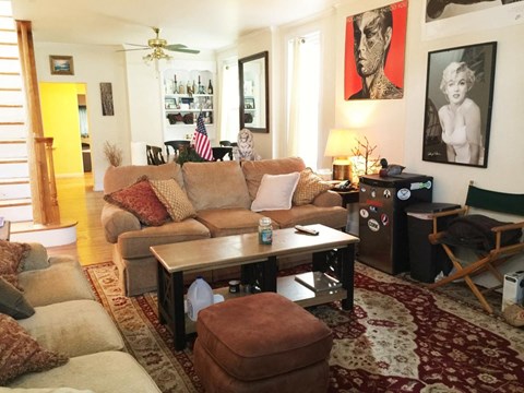 A living room with a couch, a coffee table, and a painting on the wall.