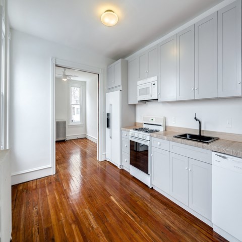 A kitchen with white cabinets and a wooden floor.