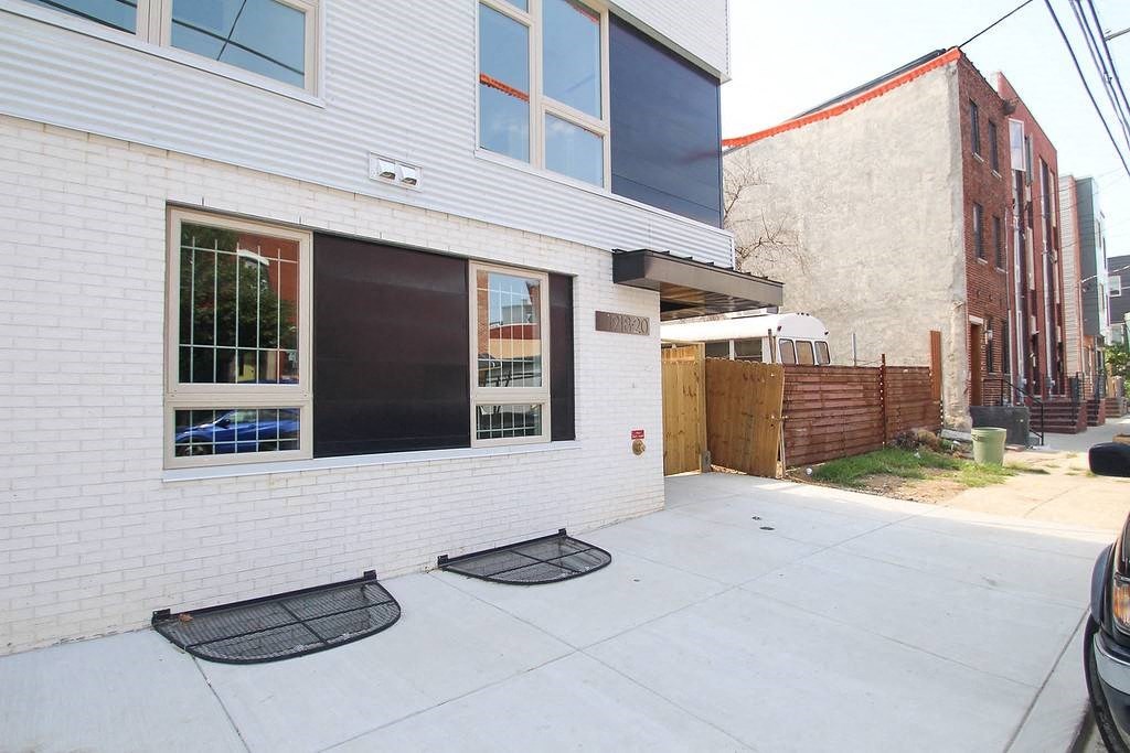 the front of a white brick building with a sidewalk and a door