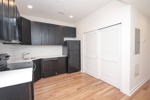 an empty kitchen with black cabinets and a refrigerator