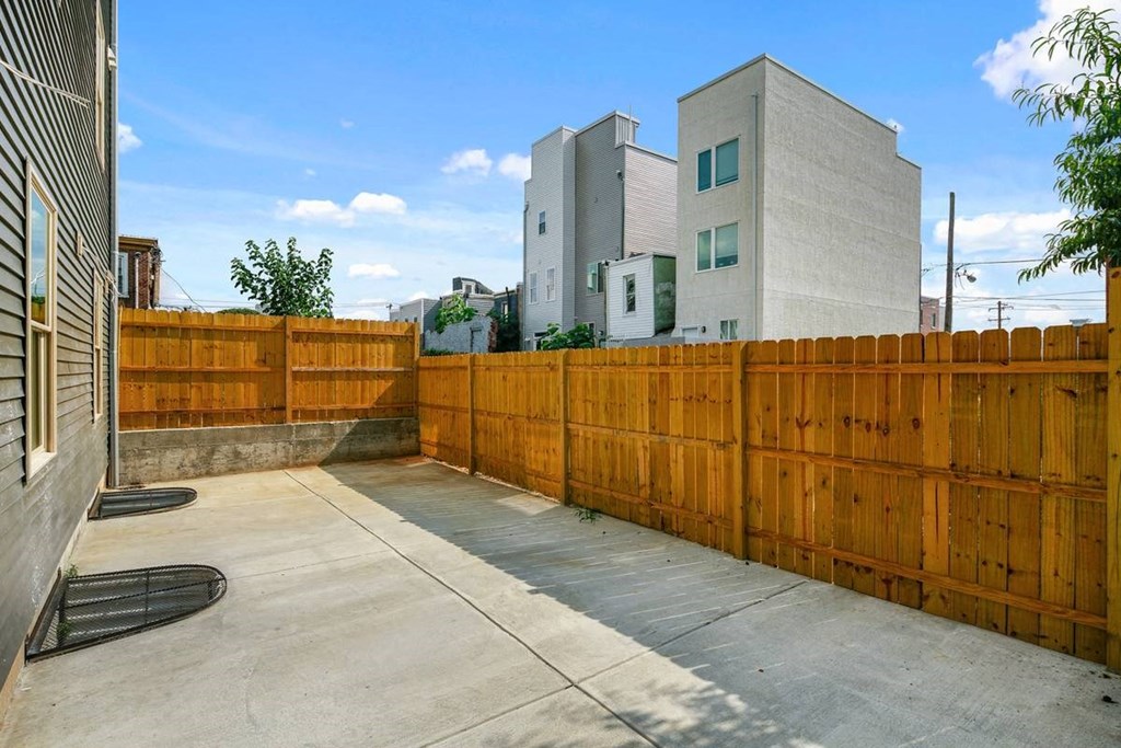 a backyard with a wooden privacy fence and apartment buildings behind it