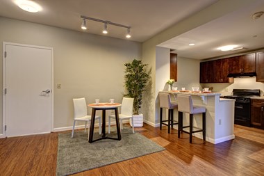 Apartment interior shows modern wood flooring and kitchen featuring a breakfast bar.