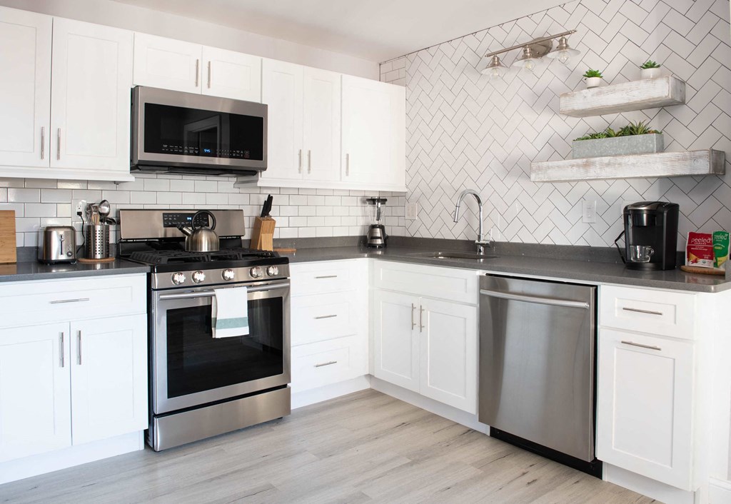 a white kitchen with stainless steel appliances and white cabinets