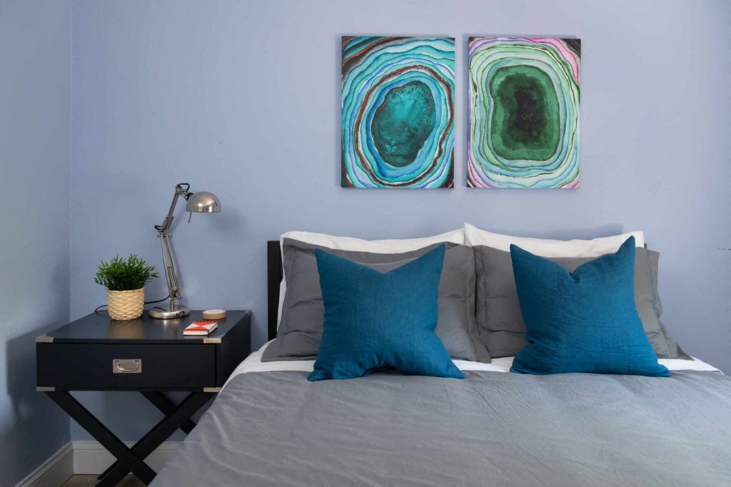 a bedroom with blue pillows and artwork on the wall