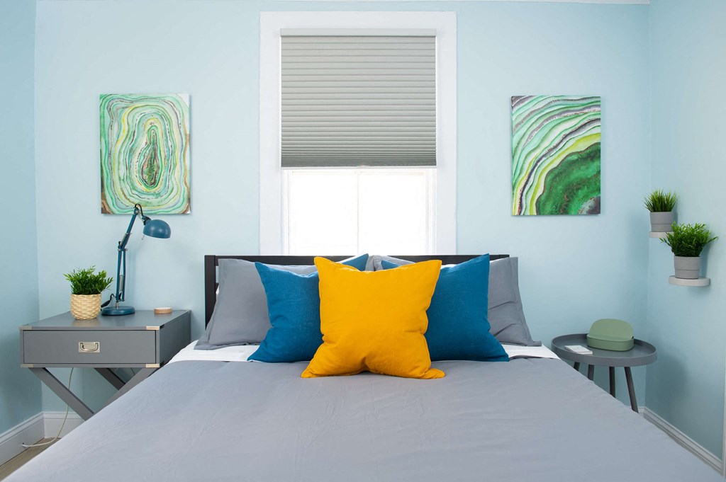 a bedroom with a bed with blue and yellow pillows