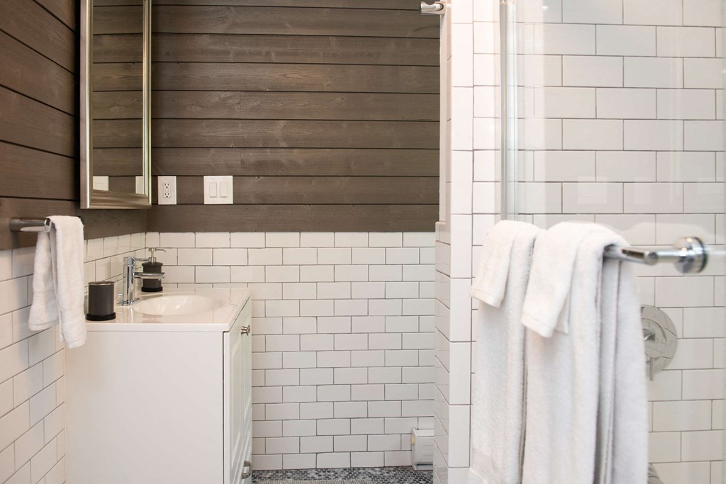 a small bathroom with white tiles and a shower and a sink