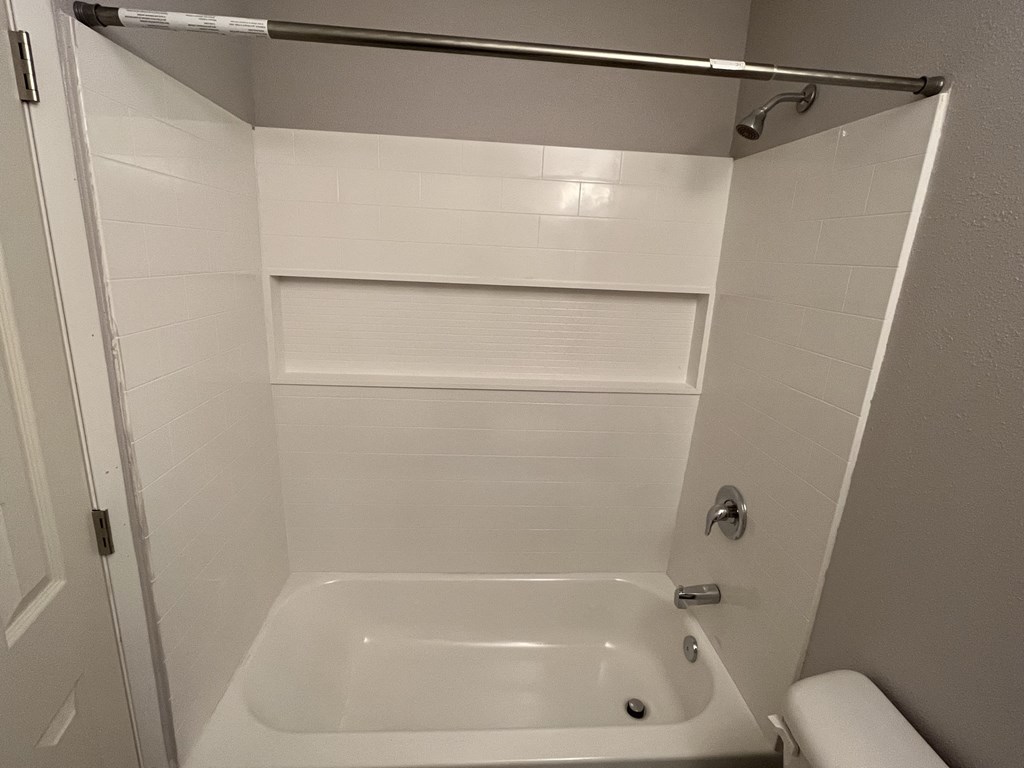a white bathroom with a tub and a shower