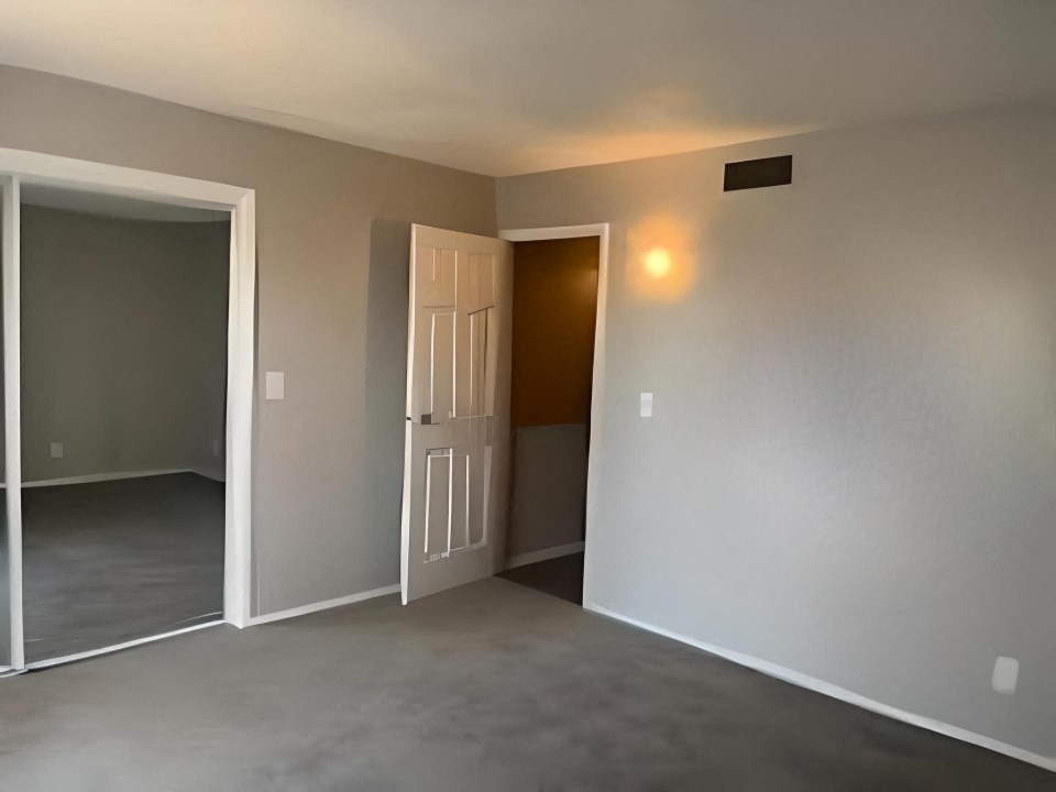 an empty living room with a door and a hallway