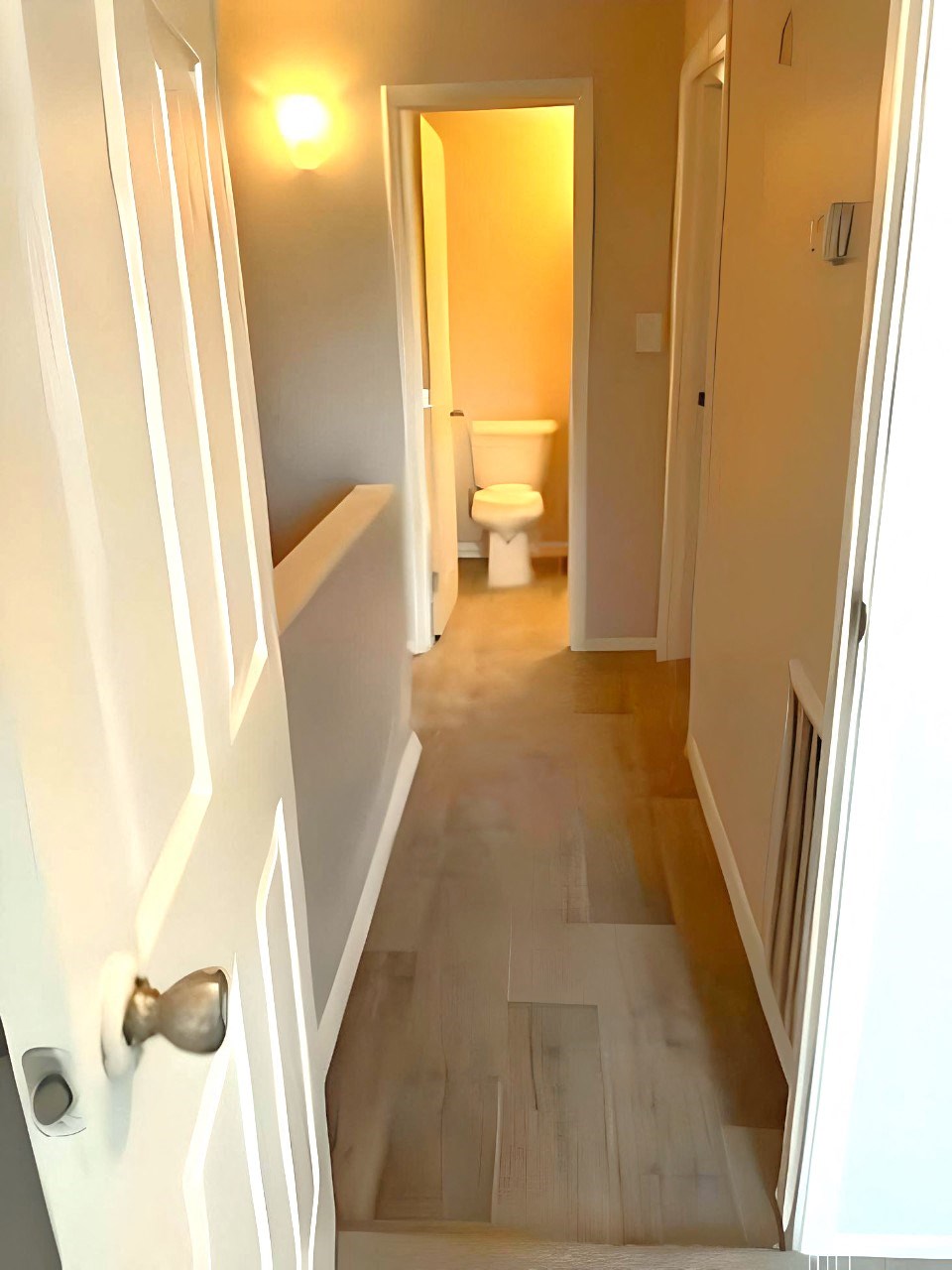a hallway with a door and a bathroom with a toilet
