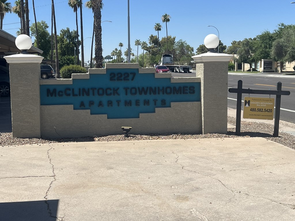 a sign for mcintock townhomes apartments on the side of a road
