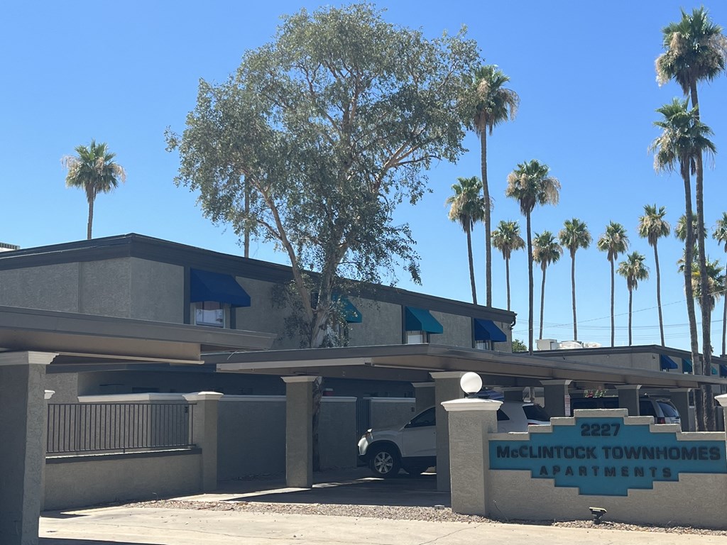 the front of a building with palm trees in front of it