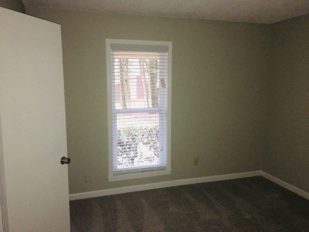 an empty room with a window and wooden floors