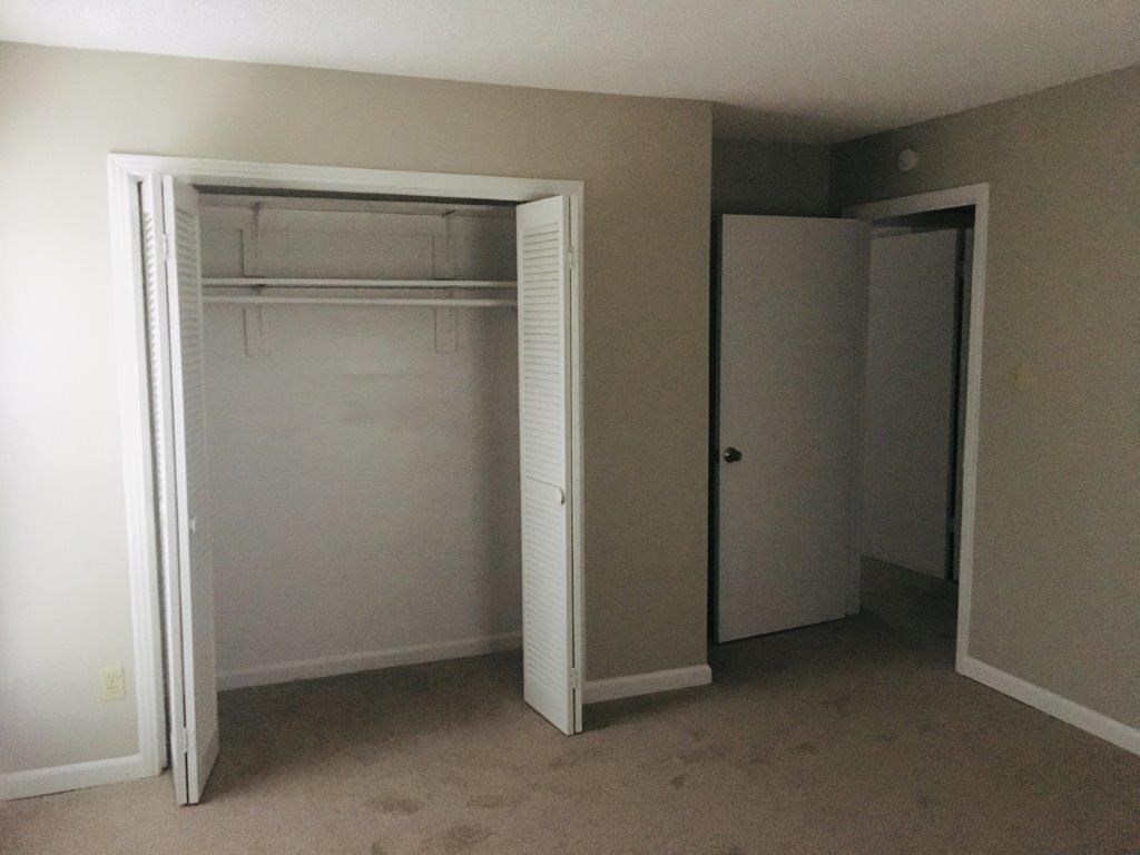 an empty bedroom with a closet and a door open