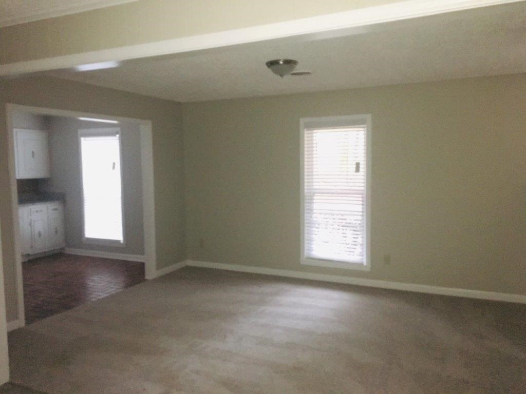an empty living room with a hard wood floor and a window