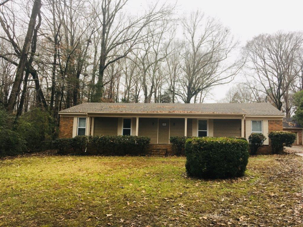 a small brown house with trees in the background