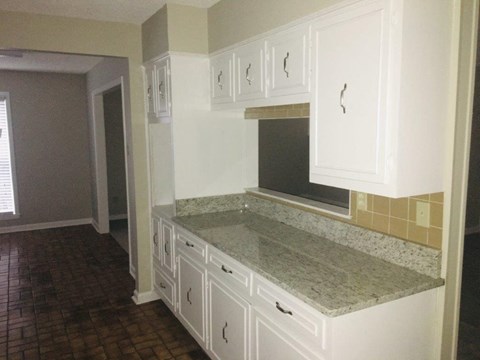 an empty kitchen with white cabinets and a counter top