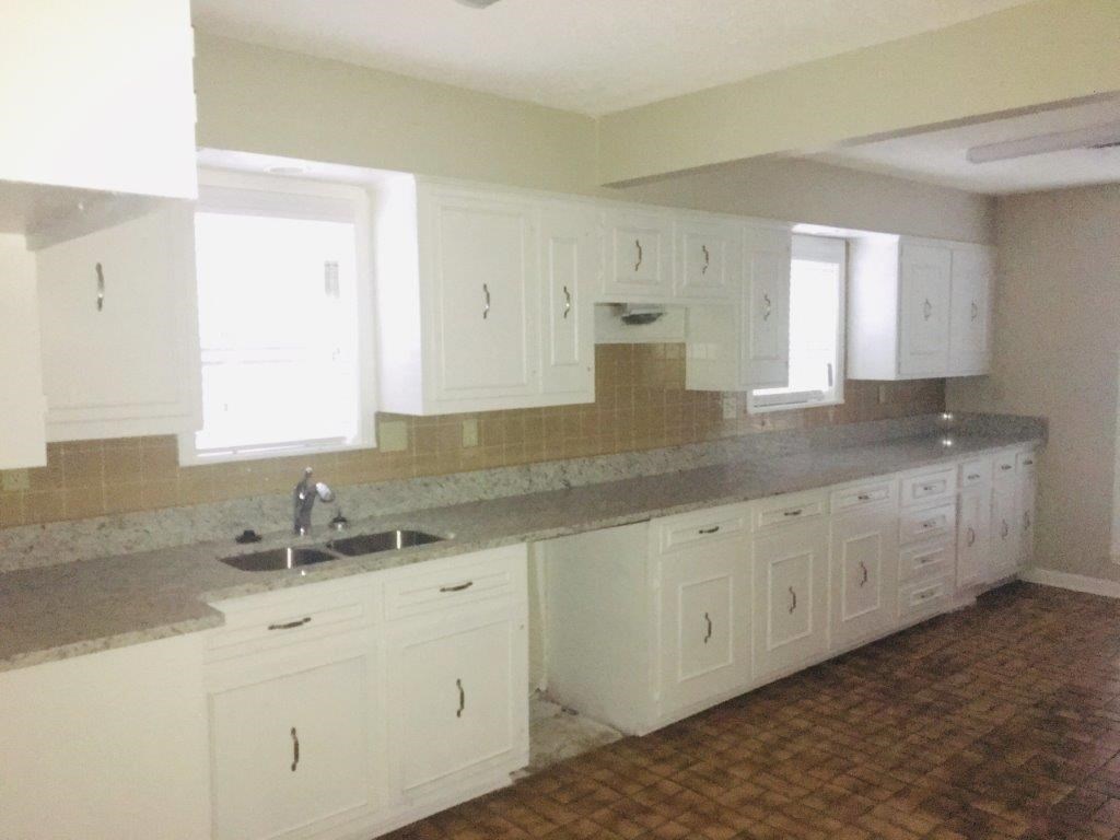 an empty kitchen with white cabinets and a sink