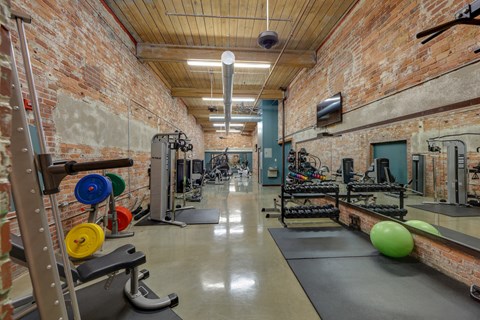 A gym with a brick wall and a variety of exercise equipment.