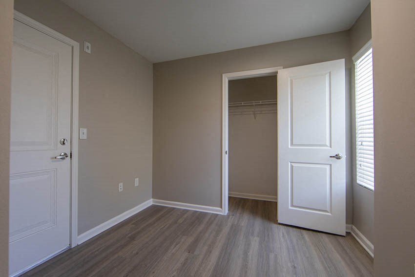 an empty bedroom with a closet and a white door