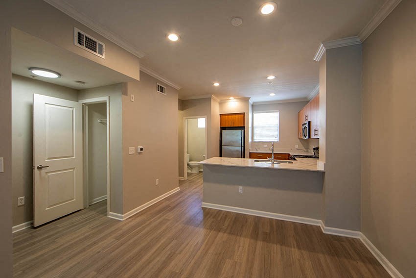 an empty living room with a kitchen and a sink