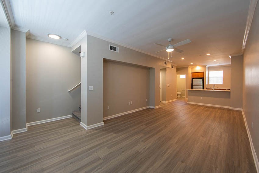 an empty living room with wood floors and a ceiling fan