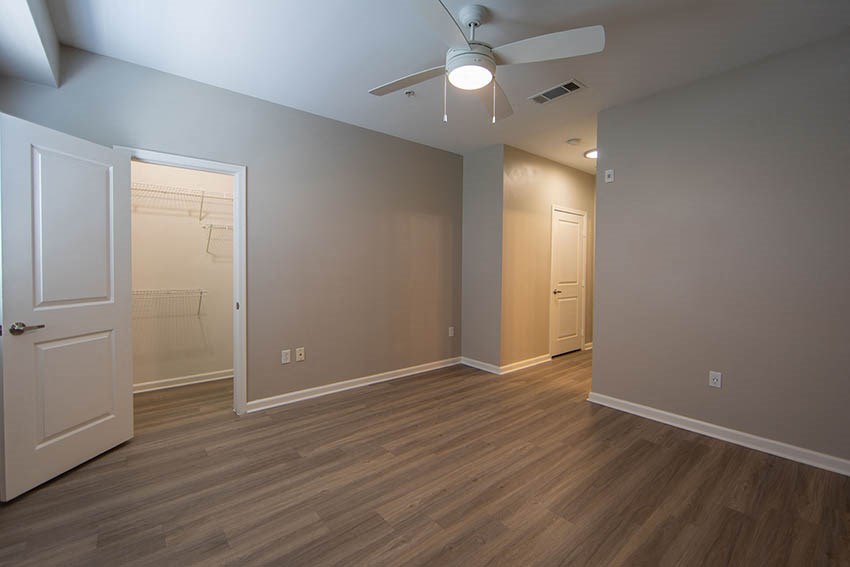 an empty living room with a ceiling fan and a closet