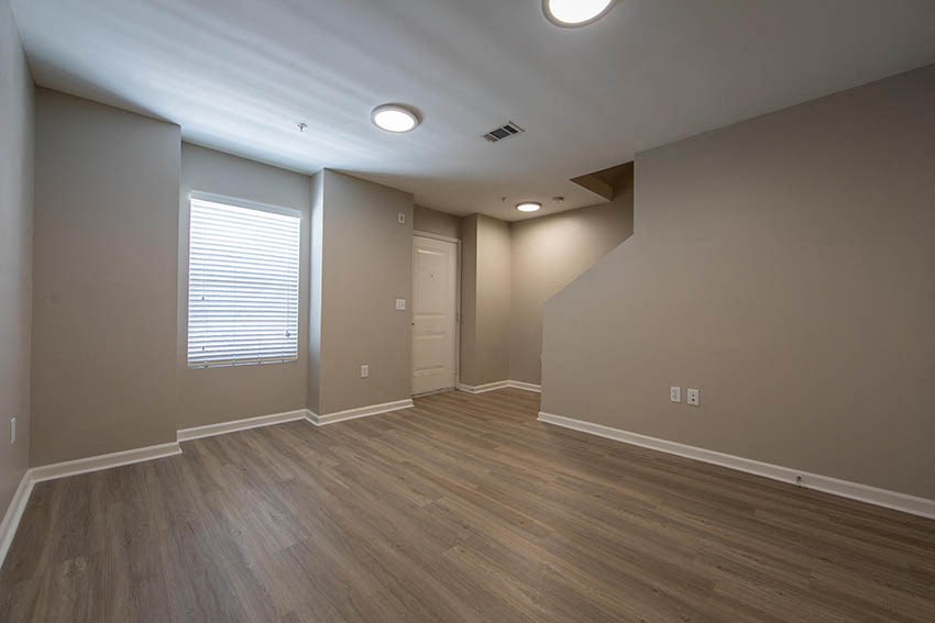 an empty living room with wood floors and grey walls
