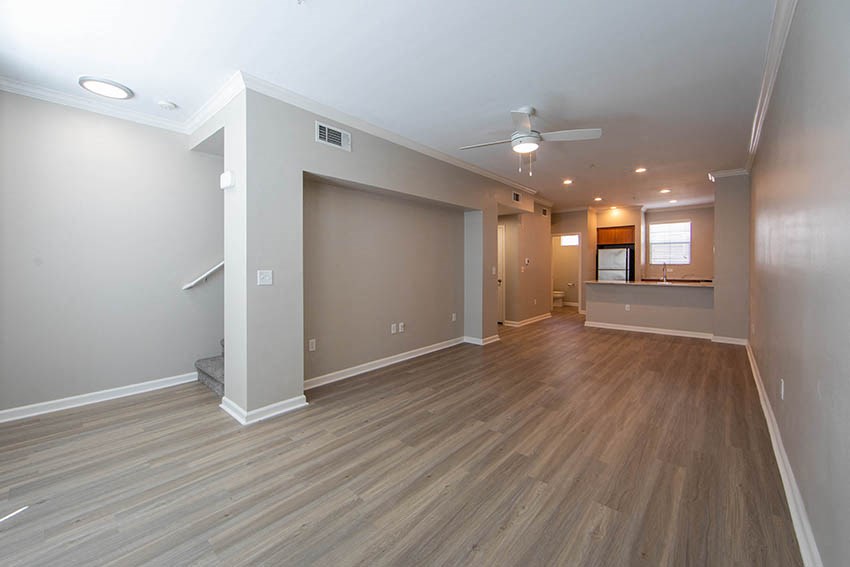 an empty living room with wood floors and a ceiling fan