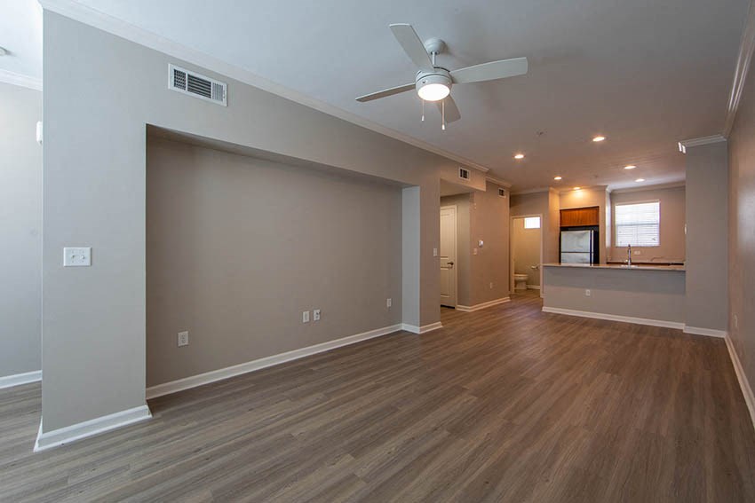 an empty living room with a ceiling fan