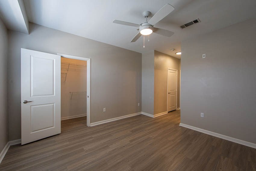 an empty living room with a ceiling fan and a closet