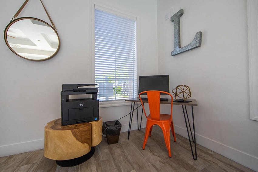 a desk with a computer and a chair in a room