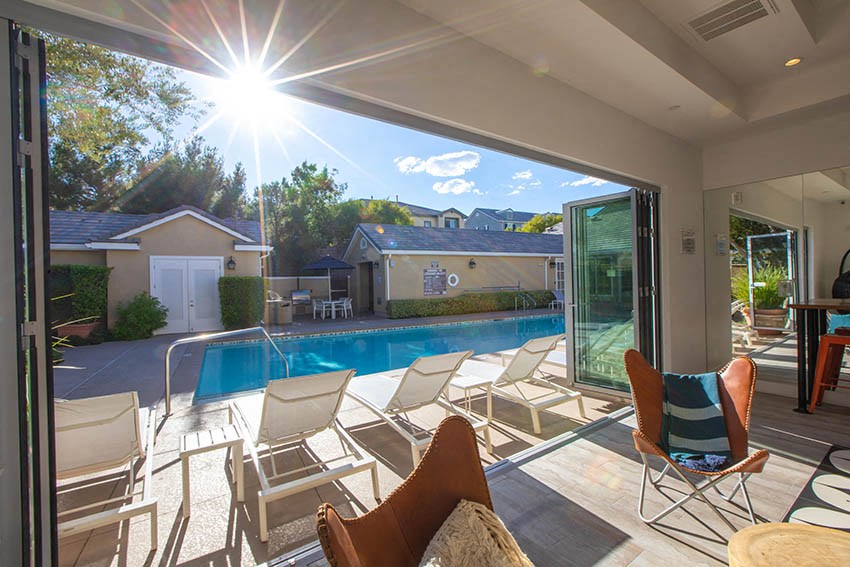 a backyard with a pool and deck with chairs