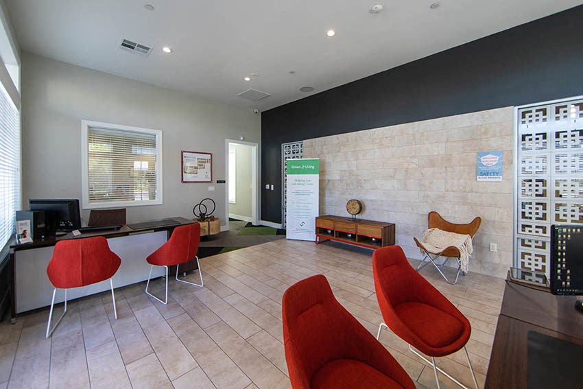 a waiting room with red chairs and a desk