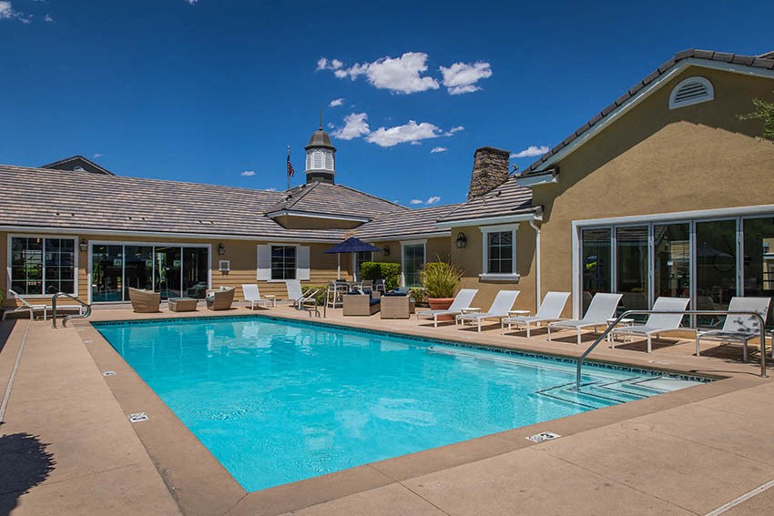 a swimming pool with lounge chairs around it in front of a building