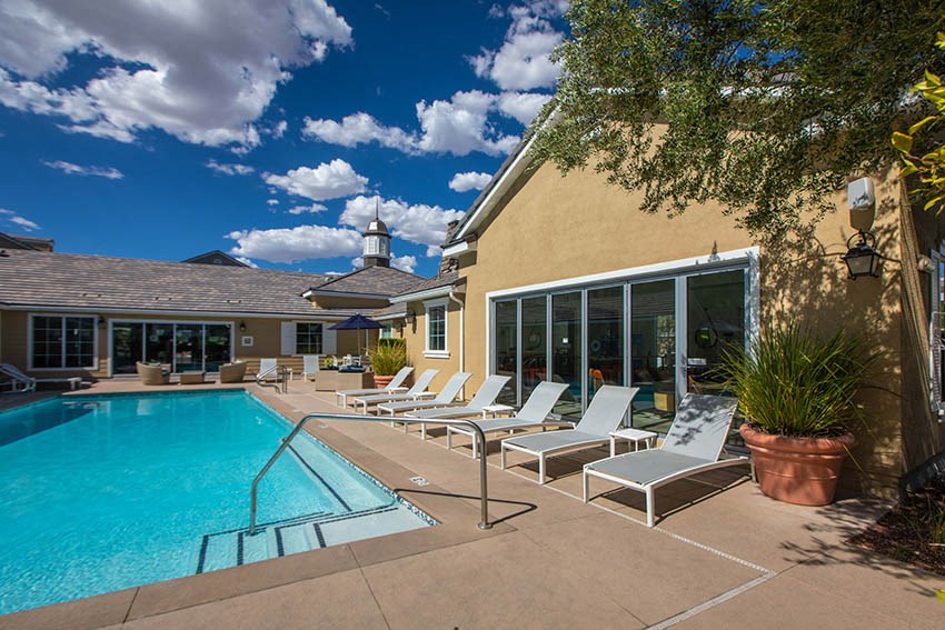 a swimming pool and lounge chairs in front of a house