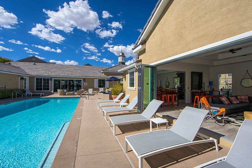 a swimming pool and lounge chairs in front of a house