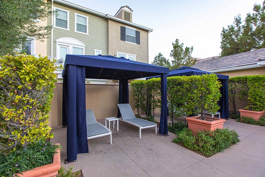 a patio with two chairs under a blue gazebo