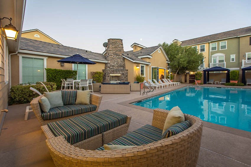 a swimming pool with chairs and umbrellas next to a building