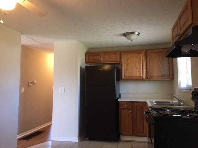 a kitchen with a black refrigerator and a stove