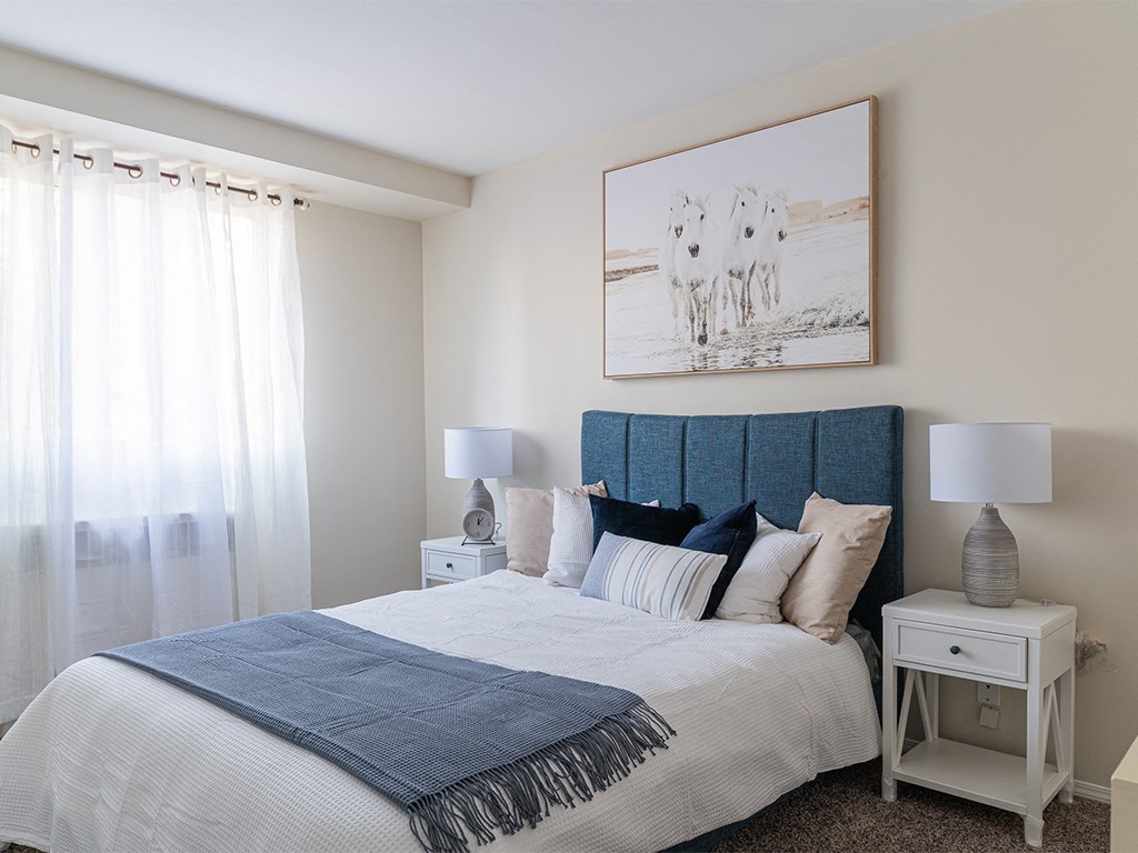 a bedroom with a bed with a blue headboard and a picture of two horses