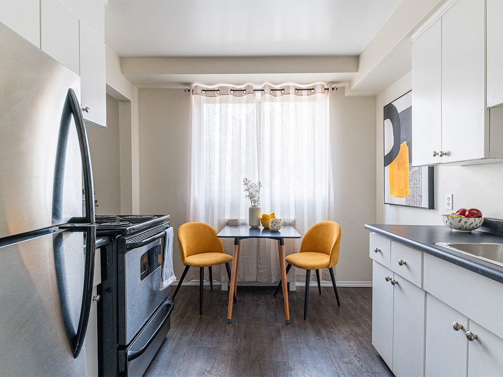 a kitchen with white cabinets and a table with two chairs
